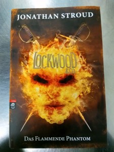 Titelbild des Buchs "Lockwood & Co. - Das flammende Phantom" von Jonathan Stroud
Feuer scheint ein Gesicht mit zwei schwarzen Augen und Mund zu formen. Auch hier kreuzen sich hinter dem Gesicht zwei Rapiere