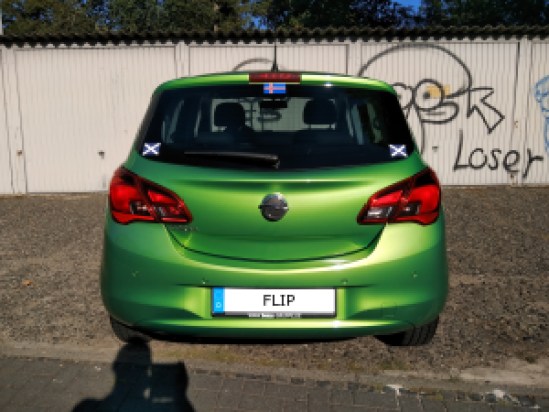 Grüner Opel Corsa von hinten, Auf dem Kennzeichen steht "FLIP"
