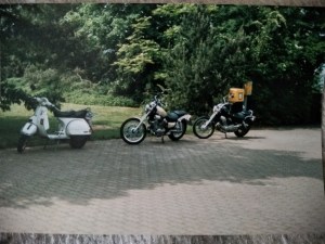Ein weißer Roller, eine helle und eine blau Virago Motorräder) hintereinander geparkt.
