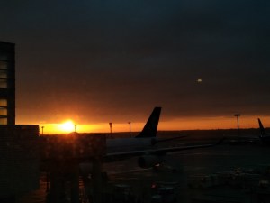 Sonnenaufgang am Flughafen
Die Sonne steht zwischen dem Horizont und einer Wolkendecke, im Vordergrund ist ein Flugzeug zu erkennen.