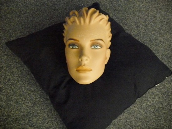 Kopf einer Schaufensterpuppe auf einem schwarzen Kissen