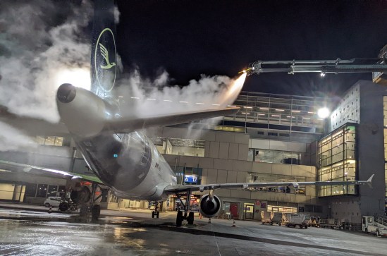Flugzeug wird enteist und steht im Sprühnebel