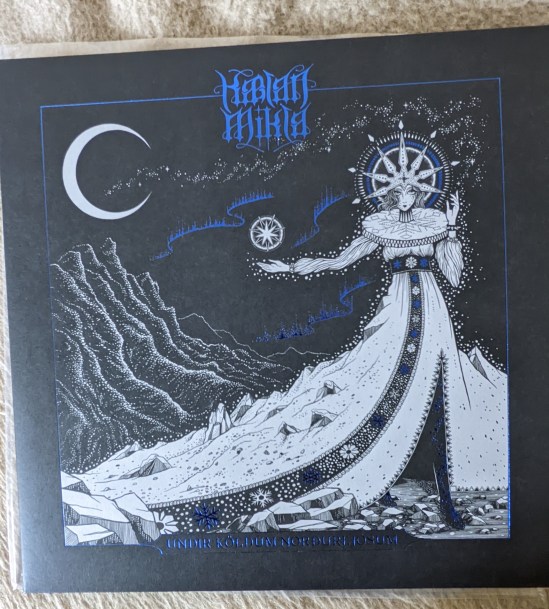 Cover der Platte Undir Köldum Norðurljósum in der Exquisite DeLuxe LP Edition von der Band Kælan Mikla Das Cover ist Schwarz, mit der Eisfrau aus den Mumin-Geschichten, der "Kælan Mikla", die mit ihrem Kleid die Landschaft mit Schnee und Eis überdeckt. Über ihrer rechten Hand schwebt ein siebenzackicker Stern in einem Kreis - wie eine Art Schneeflocke - und sie trägt eine siebenzackicke Krone. Der Schriftzug von Kælan Mikla und dem Titel ist einem leuchtenden Blau gehalten, in der selben Farbe wie ein 3 Nordlichter auf dem Cover.