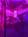 rötliches Licht und grünlich leuchtende Fingernägel über Gitarrensaiten