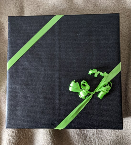 Schwarzes quadratisches Geschenk mit grünen Geschenkband