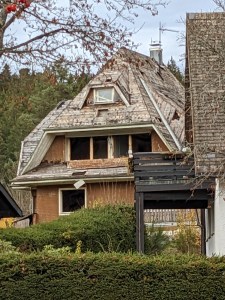 Typisch geformtes Schwazwaldhaus, jedoch im Bauzustand: Nur das Dachfenster ist vorhanden, alle anderen Fensteröffnungen sind ohne Fenster. Man kann in das Haus hineinsehen. Das Dach ist nicht mit Ziegeln gedeckt, sondern nur mit Holz bedeckt.