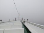 Oberdeck einer Fähre, bei der das Hinterteil des Decks schon fast wieder im Nebel verschwindet.