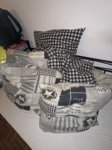 5 Kissen auf dem Bett. 2 karierte, 3 mit Muster