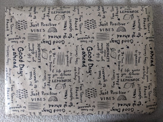 Geschenkverpackung Ein weißes Packet auf denen lauter Sprüche stehen wie "Good Days ahead" "Just Poitive Vibes" "if life gives you lemons make LEMONADE" usw