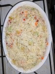 Aufflaufform voller Kartoffel-, Kohlrabi- und Karottenstücken samt Tomaten - mit viel geraspeltem Käse belegt