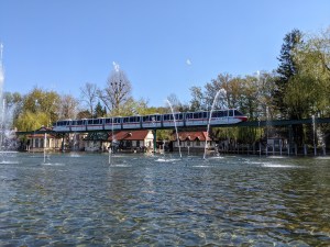 Ein See mit verschiedenen Wasserfontänen, darüber sieht man dden Europapark-Express fahren