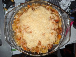Kartoffel-Kohlrabi-Gratinversuch in Glasschüssel, mit Käse überbacken. Der Käse ist aufgrund der Menge in der Mitte noch als geriebener Käse zu entziffern, außen ist er schön braun