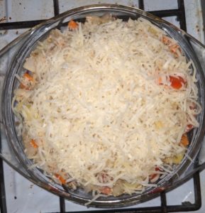 Glasschüssel mit einer großen Menge geriebenen Streukäse auf dem Inhalt der Schüssel
