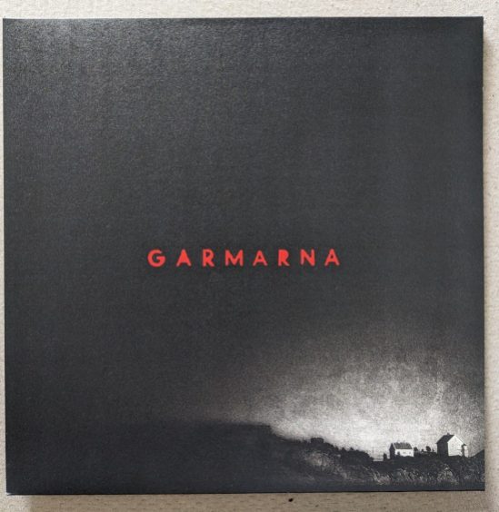 Cover der LP "6" von GARMARNA Rechts unten im Eck sind ein zwei Häuser vor hellem Hintergrund zu sehen, während der Rest der Seite Schwarz ist