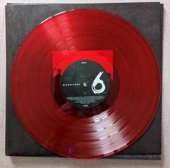 Vinyl-Platte "6" der Band GARMARNA Die Farbe der Platte ist ein leicht transparentes Rot.