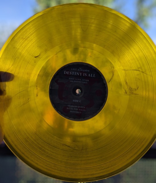Amber-farbende Vinyl-LP, gegen das Licht gehalten, von The LAST KINGDOM Side C Shadow Queen Blues for Halig Banished