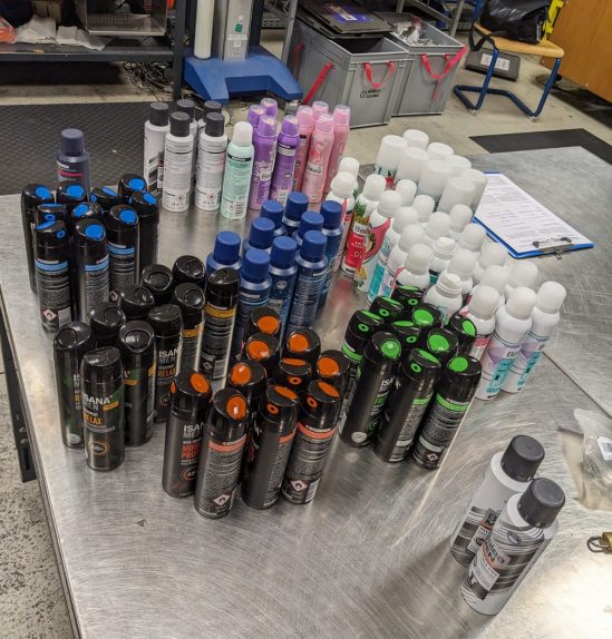 Viele Deo-Spraydosen, nach Sorten gebündelt auf dem Tisch stehend - um die 80 Stück