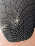 Lauffläche meines Autoreifens. In der Mitte steckt eine Mutter samt Unterlegscheibe aus Metall.