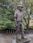 Statue eines Arbeiters mit einer Metallstange auf der Schulter - auf der eine Taube sitzt