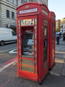 Rote Telefonzelle Zu sehen ist ein Geldautomat in der Telefonzelle, oben mit der Aufschrift FREE CASH an der rechten Seite ist noch ein Telefon zumn Telefonieren, oben mit Aufschrift TELEPHONE