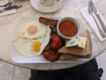 Original Englisches Frühstück, bestehend aus 2 Spiegeleiern, gebackene Tomate und Speck, Würstchen, gebackene Bohnen in Tomatensoße, Butter und Toastscheiben