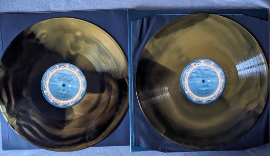 Die beiden Vinyl-Platten vom Sandman-Soundtrack. Die Farben wirbeln zwischen Dreams Schwarz und dem Gold von Sand.