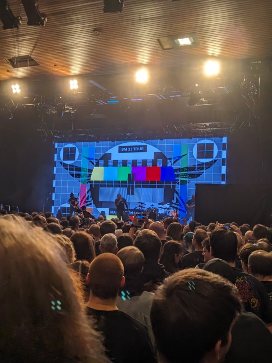 Testbild auf der Leinwand in der Stadthalle - darauf steht BM 23 Tour davor viele Köpfe von hinten
