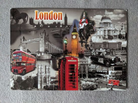 Postkarte von London, hauptsächlich in Schwarz-Weiß, doch die roten Doppeldeckerbusse, der Big Ben, die roten Telefonzellen und die rote Uniform eines Soldaten zu Pferd sind in Farbe, genau wie der Schriftzug "London".