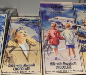 Schokolade der Starbrook Airlines. Links Dunkle Schokolade mit Mandeln, mit einer Pilotin mit Lederjacke als Motiv - 400g. Rechts eine Propellermaschine, auf die zwei Kinder zugehen - Milchschokolade mit Haselnuss. Auch 400g.
