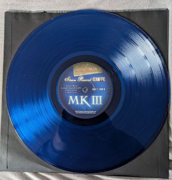 Dunkelblaue Vinyl-Platte Aufschrift des Innenlabels: Property of Walter Robotics Steam Powered Giraffe 1. Curtain-Raiser 2. Steam Powered Giraffe 3. Mecto Amore 4. Hatch Fever Disc 1 - Side A MK III ©2013 Steam Powered Giraffe LLC www.SteamPoweredGiraffe.com