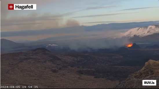 Bildschirmfoto der Eruption vom 16.03.2024 Livestream von RÚV. Unten links steht 2024-04-05 19:54:35 Oben links im Eck steht die Standortangabe der Kamera: Hagafell Zu sehen im rechten Bildbereich der Krater, in dem Lava blubbert. Über dem Krater im Hintergrund sind schneebedeckte Hügel und der Qualm des Kraters zieht nach links über die Ebene hinweg. Unten rechts steht RUV.is