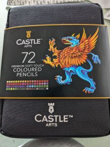 Stofftasche mit Banner darum von CASTLE ARTS 72 Premium Soft Touch COLOURED PENCILS Neben dieser Beschriftung steht ein Greif mit goldenen Flügeln und blauen Hinterteil