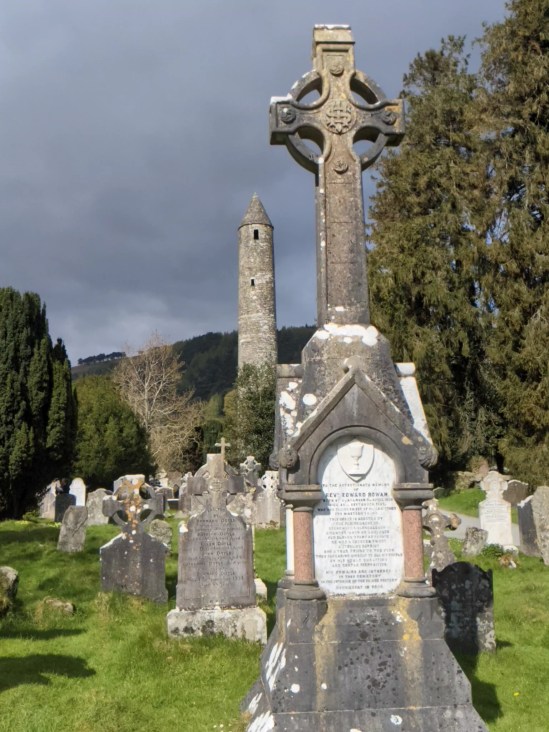 Friedhof vom Lower Lake von Glendalough. Im Vordergrund ein keltisches Grabkreuz - im Hintergrund der Steinturm.