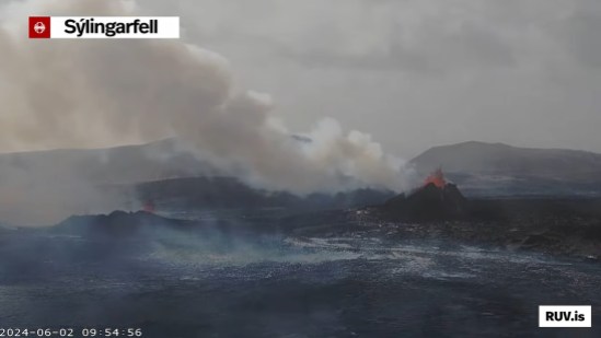 Bildschirmfoto der Eruption vom 29.05.2024 Livestream von RÚV. Unten links steht 2024-06-02 09:54:56 Oben links im Eck steht die Standortangabe der Kamera: Sýlingarfell Rechts im Bild ist ein Krater, der Lava spuckt und qualmt, links ein kleinerer Krater, über dem ebenfalls Lava zu sehen ist. Der Vordergrund sieht feucht aus und es steigen ebenfalls Schwaden davon auf. Unten rechts steht RUV.is