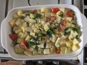 Auflaufform mit kleingeschittenen Kartoffeln, Kohlrabi, Spinat, Zwiebeln und Tomaten.