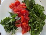 Kleingeschnittene Kohlrabiblätter links, geviertelte Cherrytomaten in der Mitte und kleingeschnittenen Blattspinat rechts