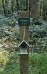 Schild an einem Holzpfahl im Wald: Guilia Vinciguerra zur Taufe 6. Januar 2018 darunter hängt ein Miniatur-Vogelhäuschen am Pfahl