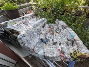Mit Zeitungspapier verkleidete Innenteile der Drehleiertasche. An manchen Stellen sieht das Papier noch feucht vom Tapetenkleister aus.