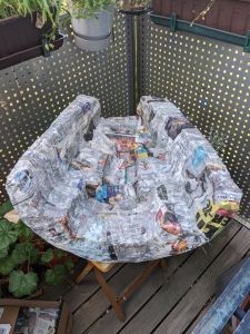 Mit Zeitungspapier verkleidete Innenteil der Drehleiertasche. An manchen Stellen sieht das Papier noch feucht vom Tapetenkleister aus.