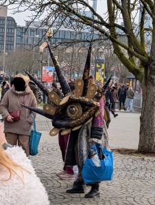 Maske eines großen Augens mit Spitzen Strahlen in Schwarz und Gold. Ein Preisschild aus Pappe sagt 65,-