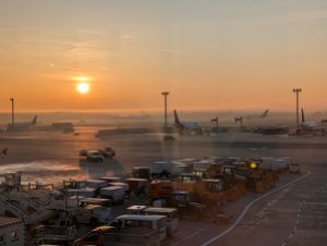Blick auf Flughafen-Rollfeld nach Sonnenaufgang mit Morgennebel über der Bahn