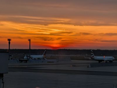 Blick auf Flughafen-Rollfeld kurz vor Sonnenaufgang, der sich tiefrot ankündigt.