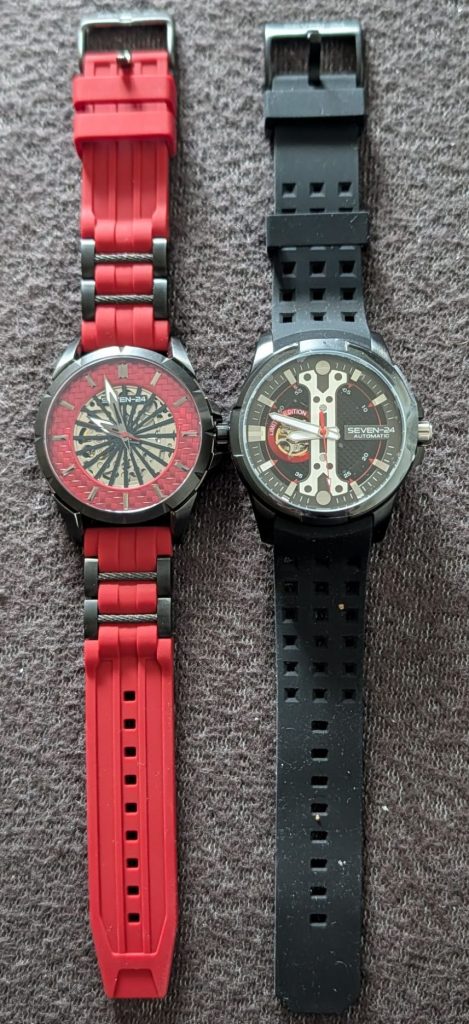 2 Armbanduhren, eine mit rotem Ziffernblatt und rotem Armband, die zweite mit schwarzem Ziffernblatt und schwarzem Armband